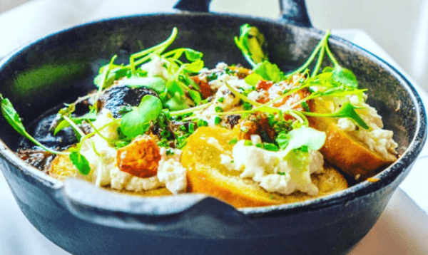 Cast-iron skillet with toast, fresh cheese and microgreens